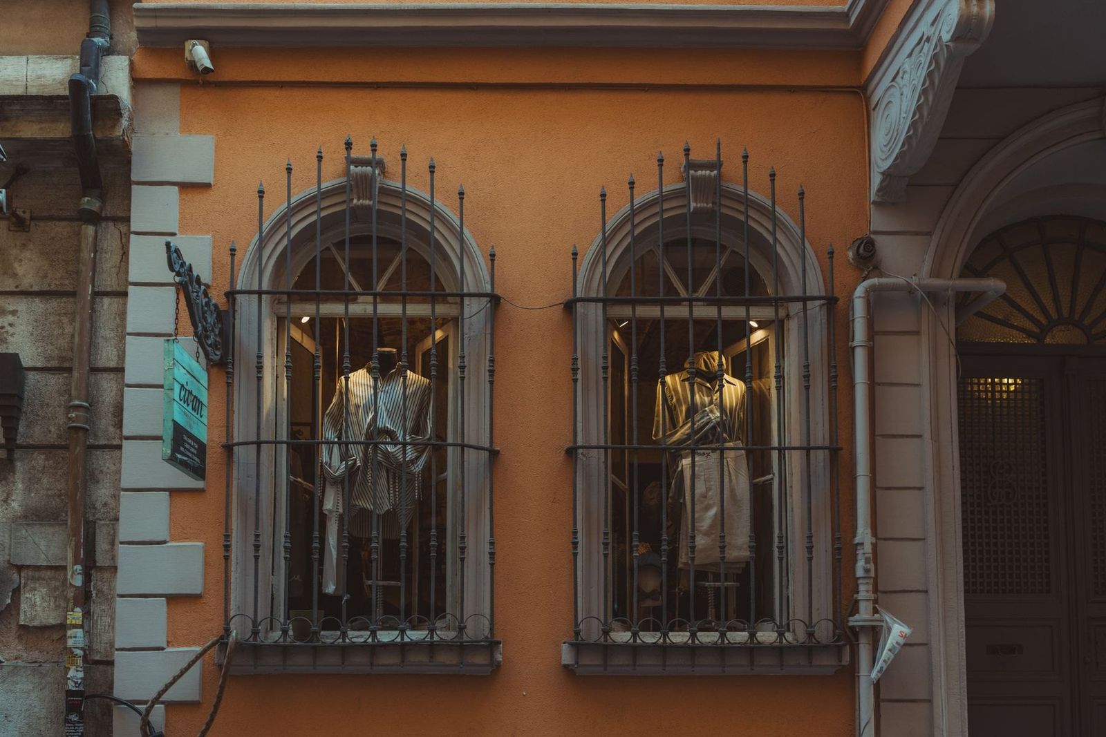 Schaufensterpuppen hinter pastellfarbener Fassade